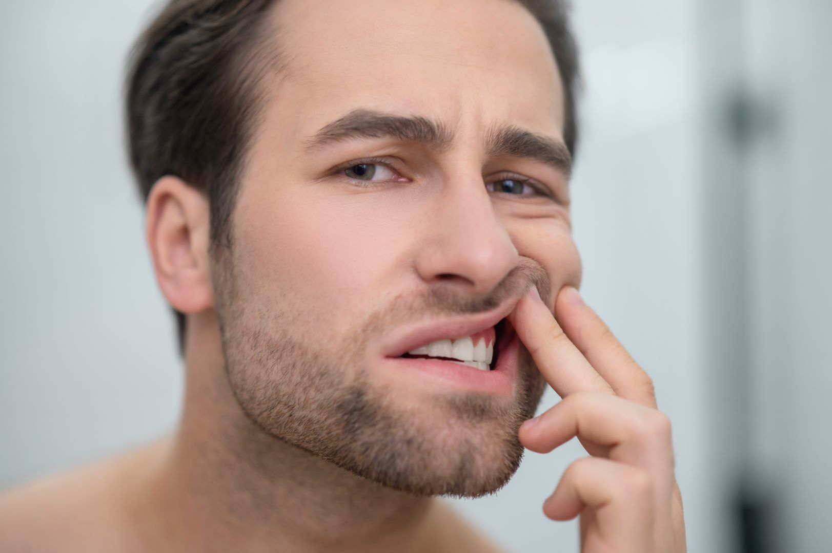 Man checking his teeth and looking disturbed Parodontologia